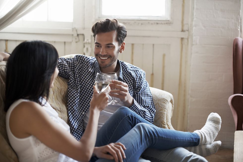 couple-sitting-on-sofa-talking-and-drinking-wine-royalty-free-image-1626859137
